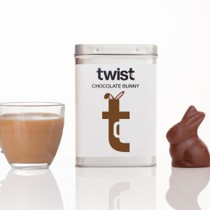 Chocolate Bunny Tisane regular caddy next to a brewed cup of Chocolate Bunny tisane and a chocolate Easter bunny