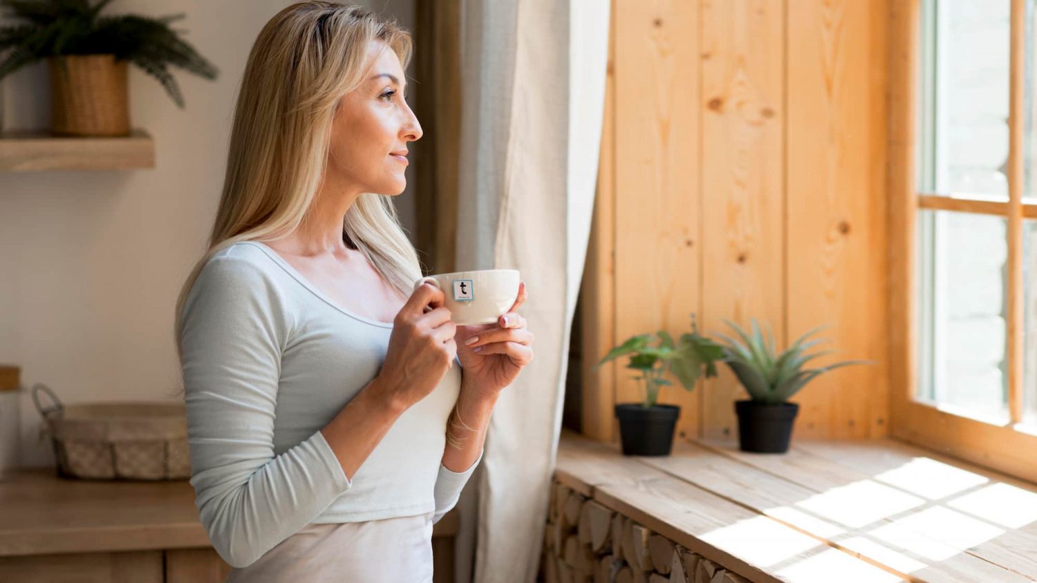 A woman having a pleasurable experience drinking Rooibos tea and gazing out a window.